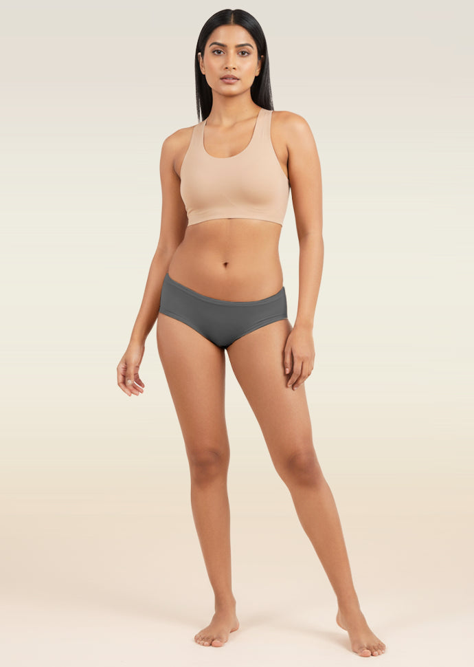 Woman wearing a beige sports bra and gray low-waist underwear on a beige background