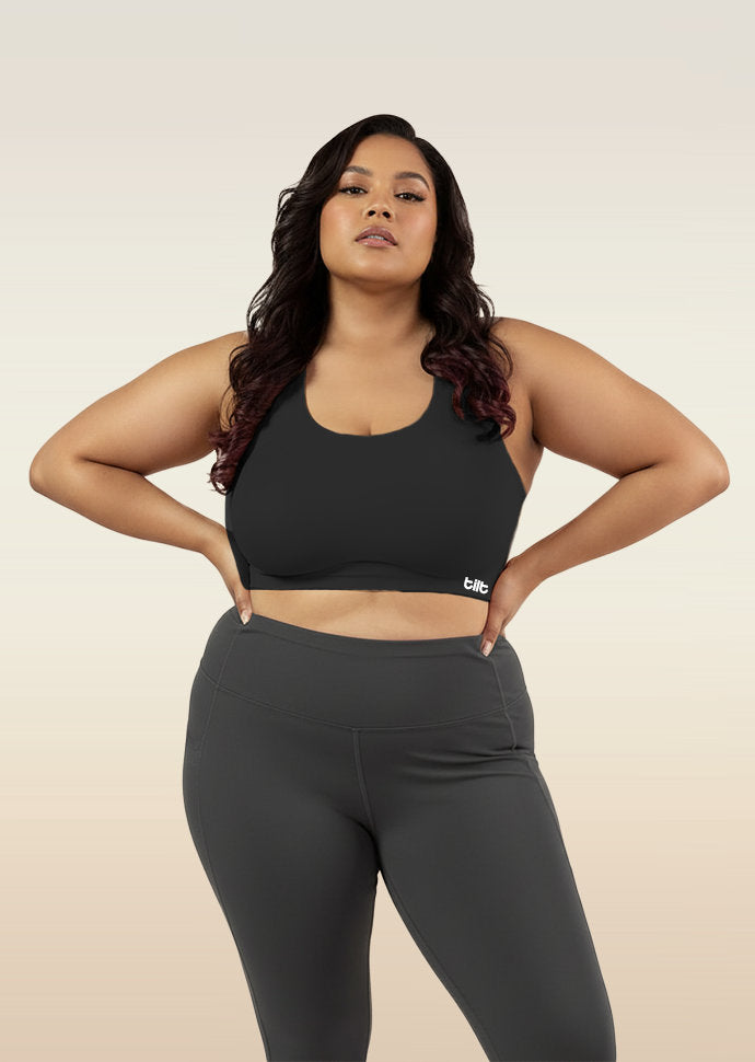 Woman wearing a black sports bra and leggings on a beige background