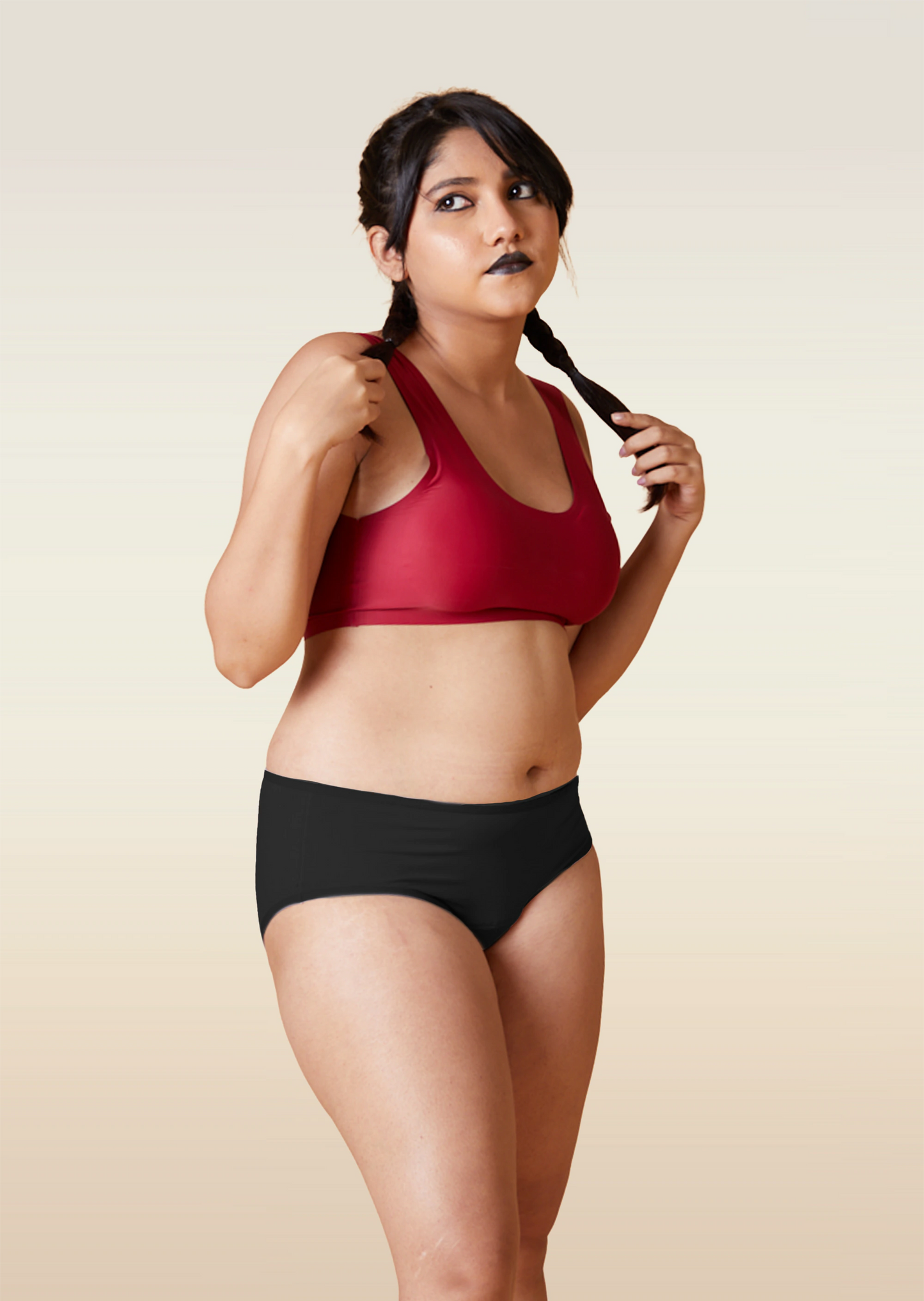 Woman wearing a red sports bra and black underwear on a beige background