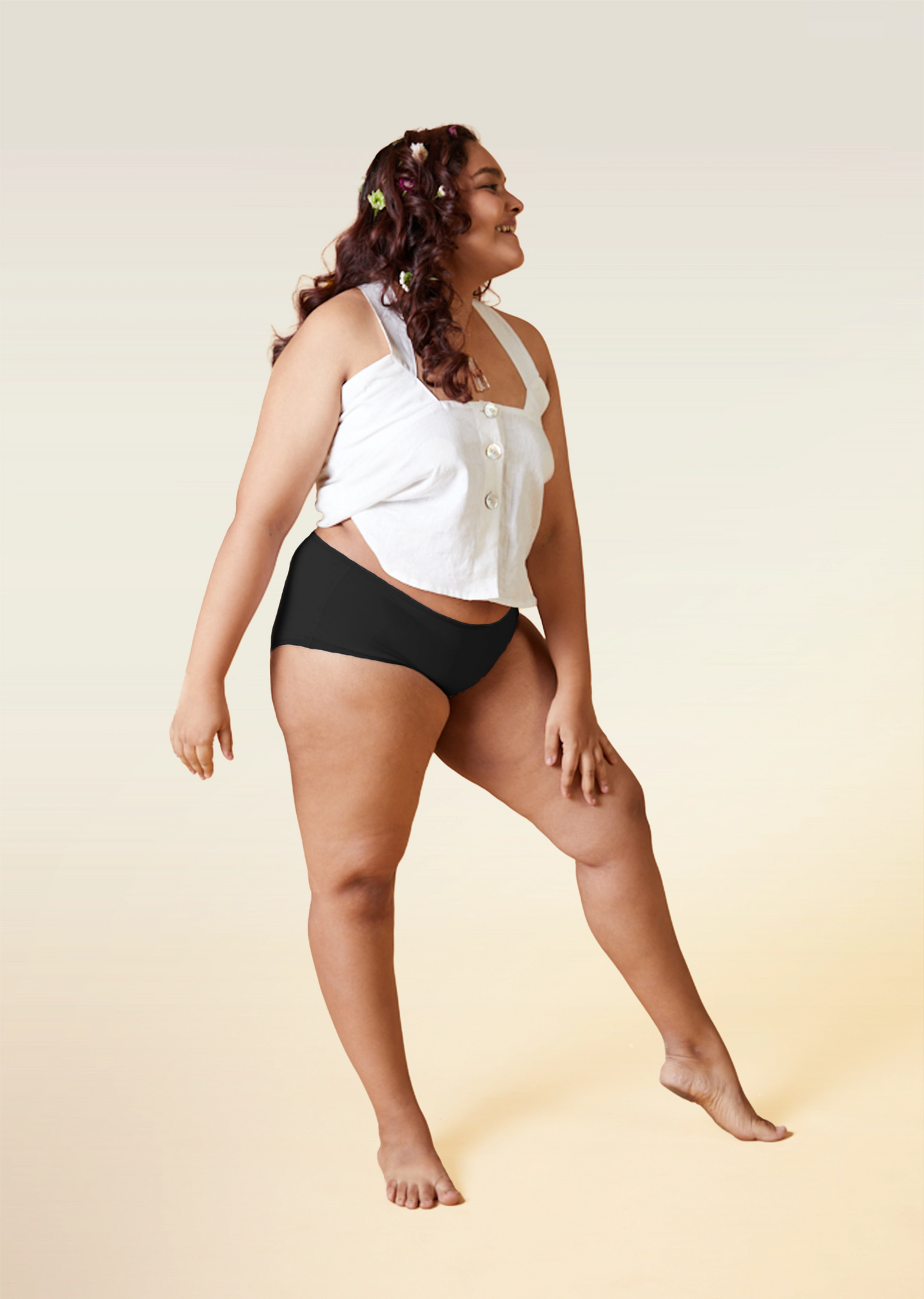 Woman wearing a white top and black underwear on a beige background