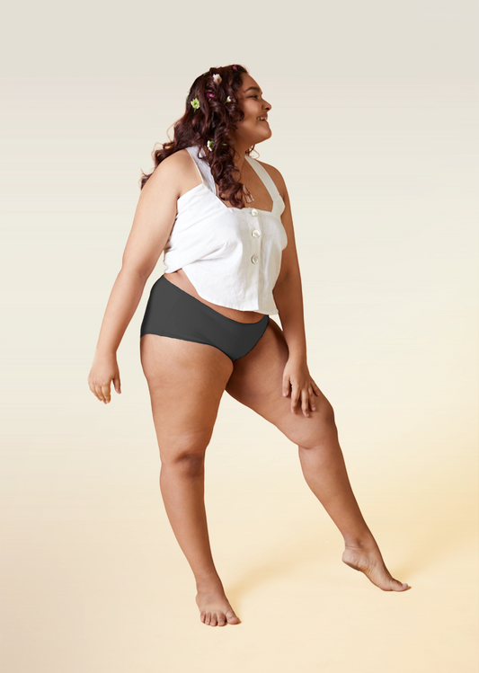 Woman wearing a white top and gray underwear on a beige background