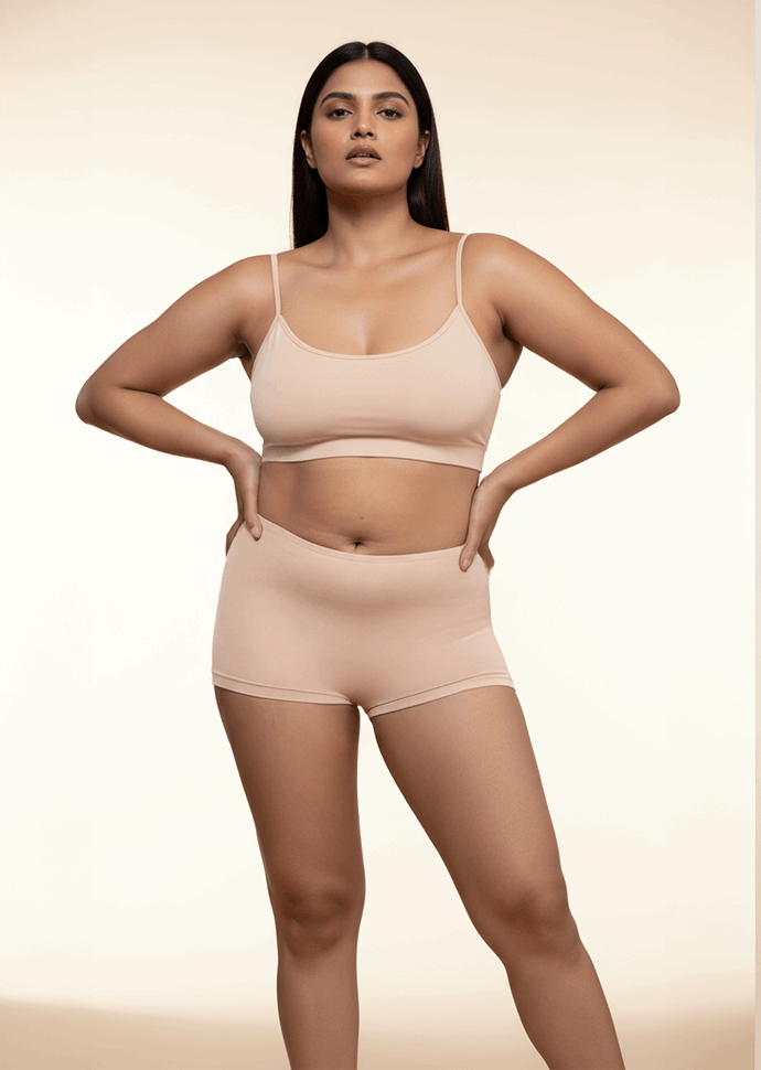 Woman wearing a beige bra and boyshorts on a beige background
