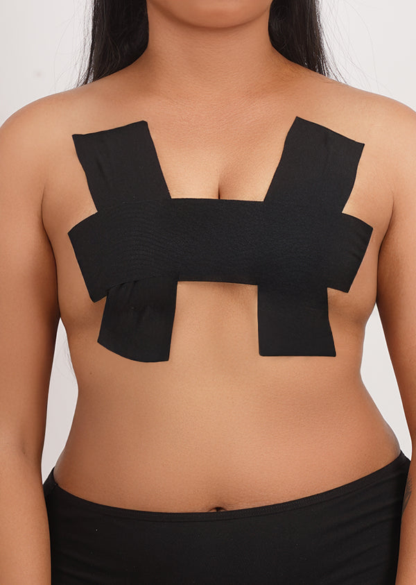 Front view of a person wearing black adhesive boob tape applied in a supportive H-pattern.