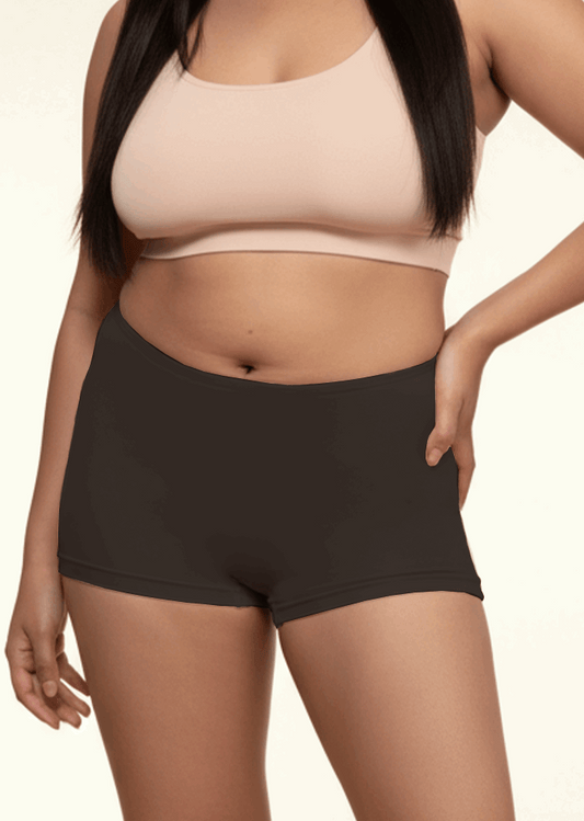 Person wearing a beige sports bra and black boyshorts on a beige background