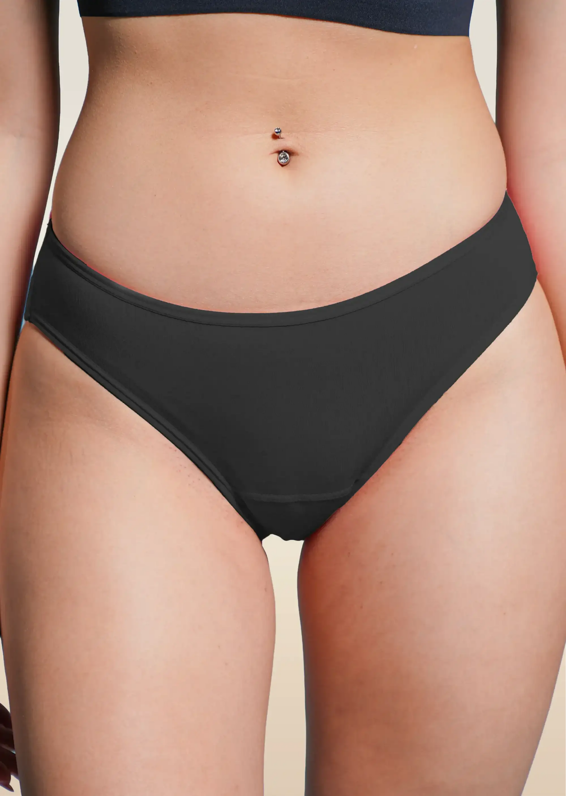 Black underwear worn by a person on a beige background