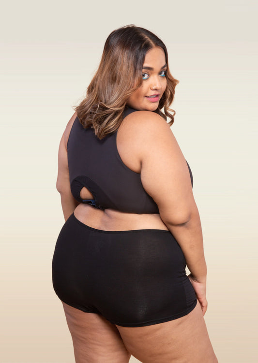 Woman wearing a black top and  boyshort on a beige background