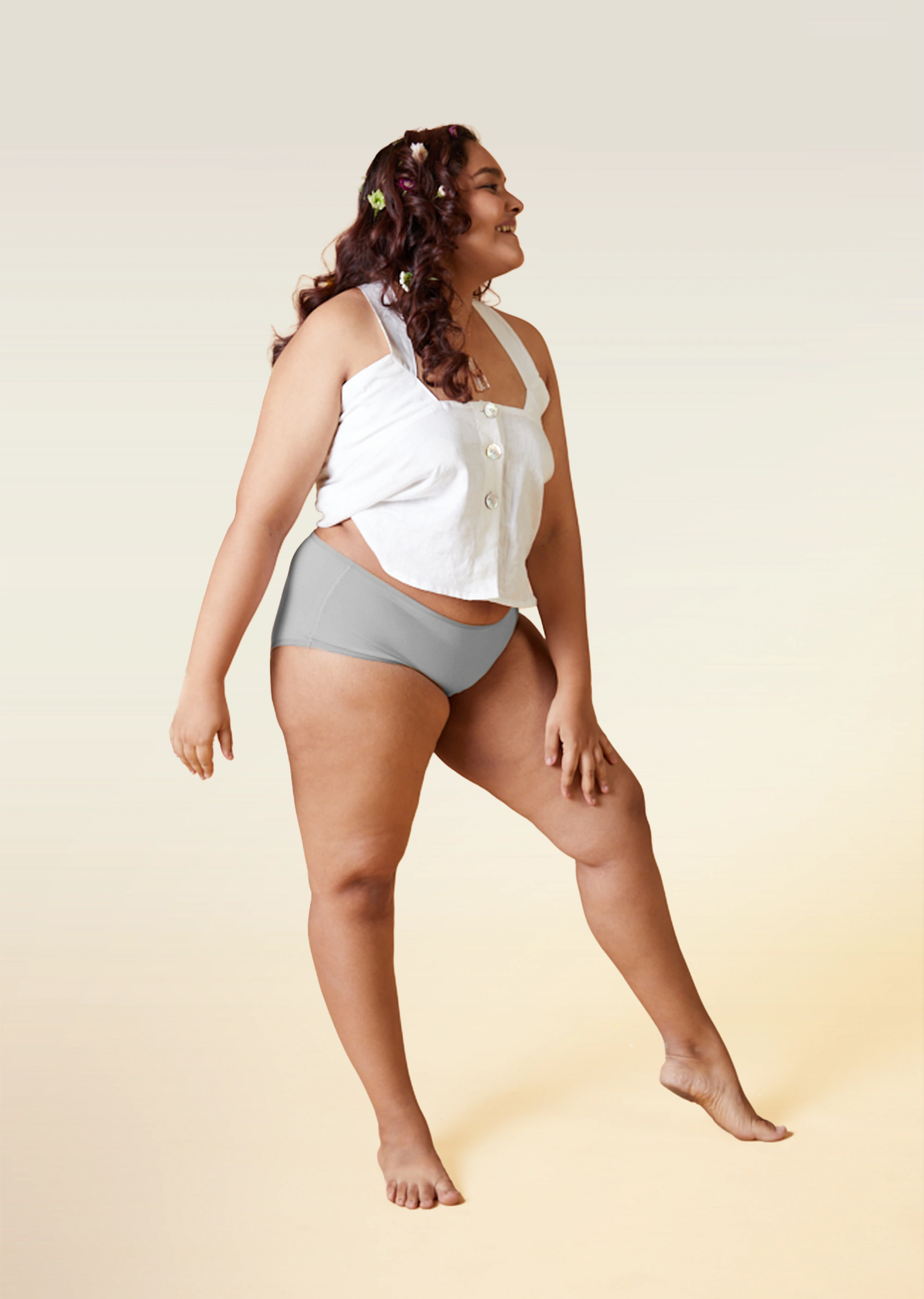 Woman wearing a white top and gray underwear on a beige background