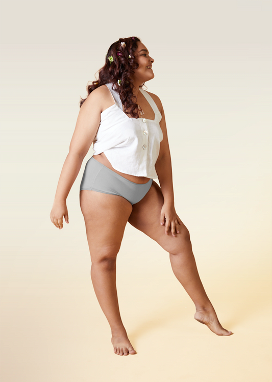 Woman wearing a white top and gray underwear on a beige background